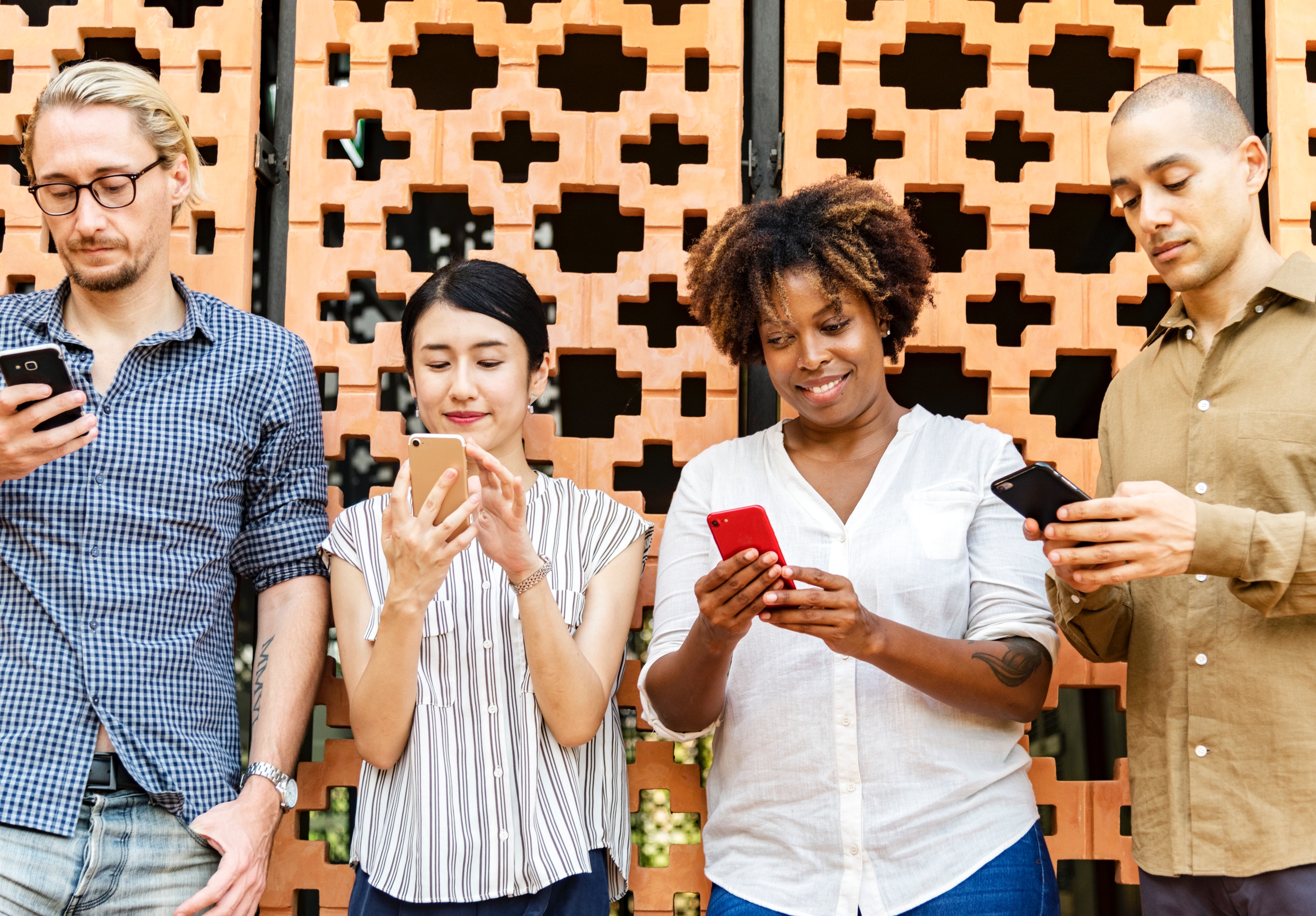 Four adults looking at their smartphones