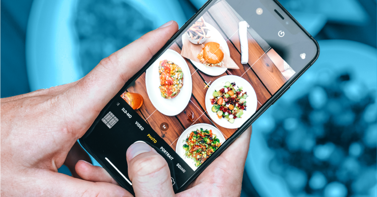 Photo of smartphone taking a photo of a table of food.